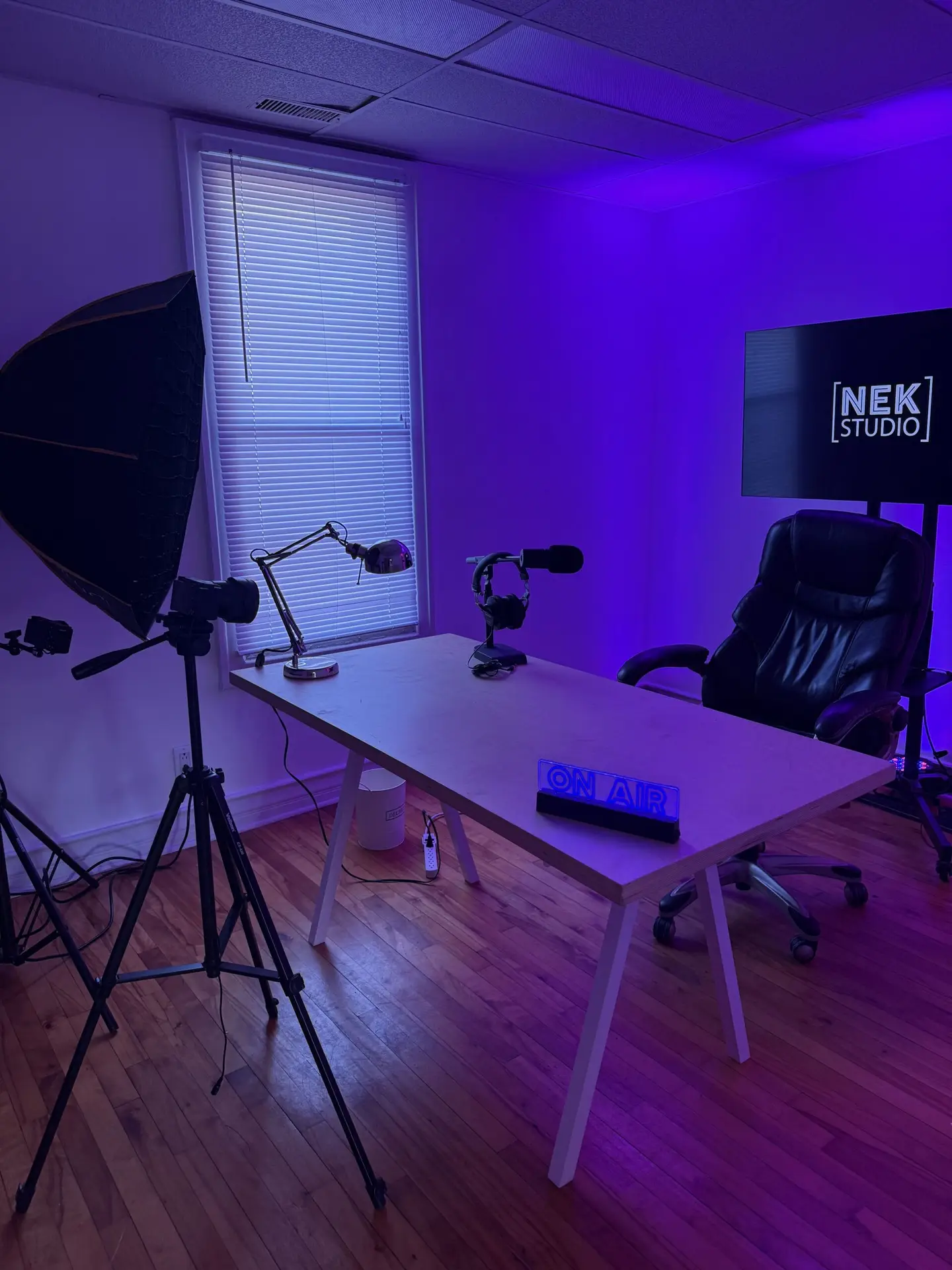 Salle de podcast professionnelle avec bureau, micros et éclairage moderne au NEK STUDIO à Lachine, Montréal.