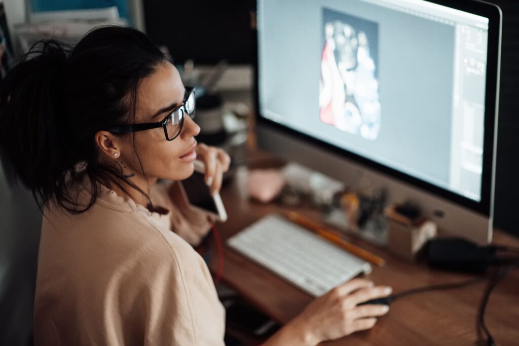 Femme travaillant sur un ordinateur portable en train de créer un design graphique pour un projet de NEK AGENCY à Montréal