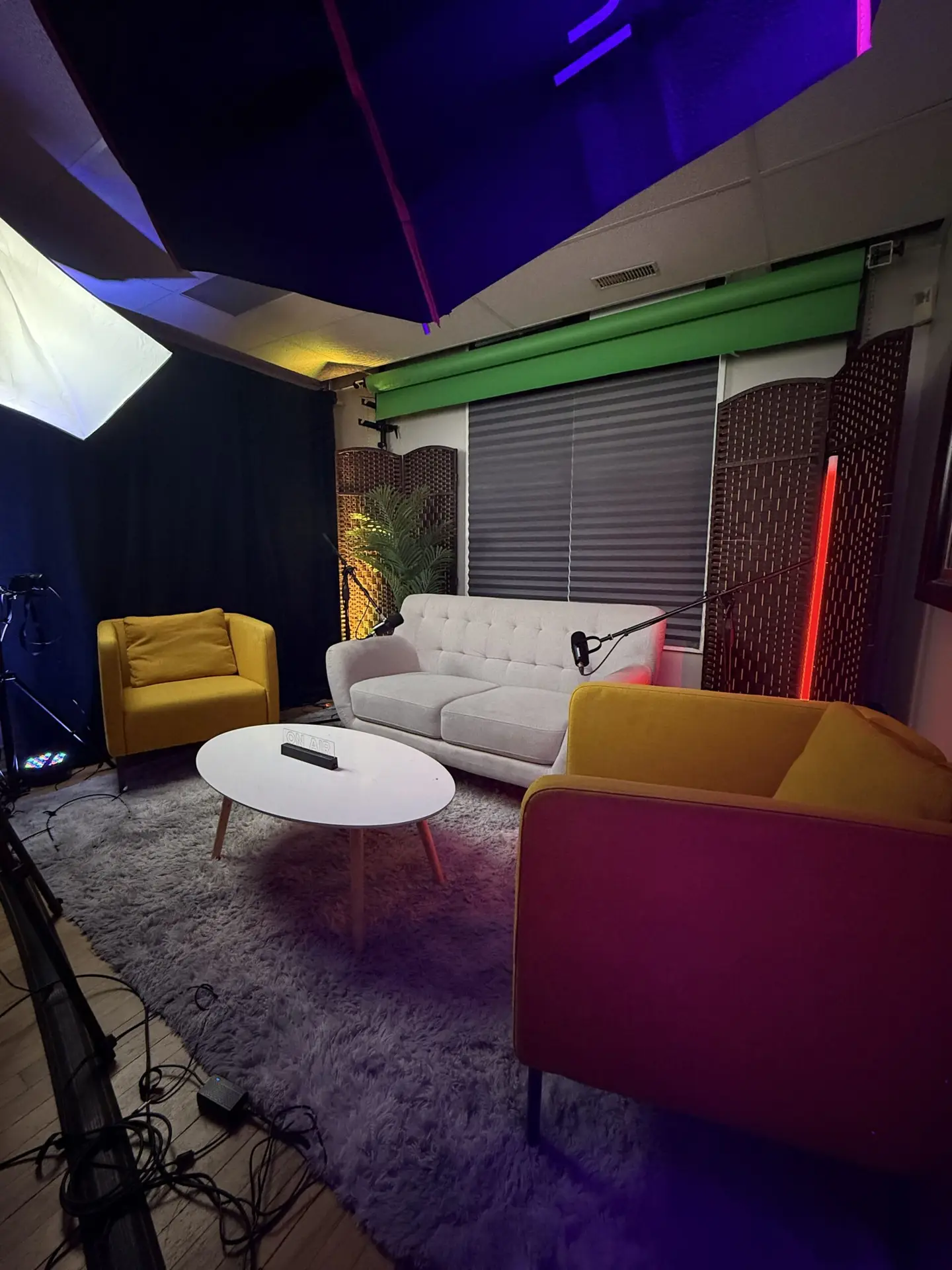 Salle de podcast avec sofa, micros professionnels et décor lumineux au NEK STUDIO à Lachine, Montréal, idéale pour les discussions en groupe et les talk-shows.